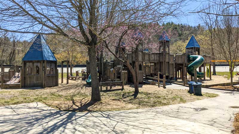 Wooden playground structure with slides shaped like a castle at Carrier Park in West Asheville