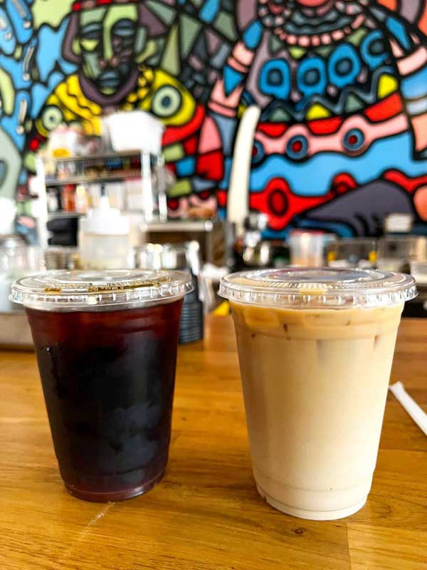 To go cold brew and iced latte in front of a colorful mural at PennyCup's downtown Asheville location