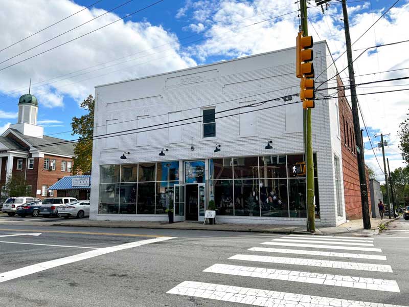 Exterior of Provisions Mercantile's West Asheville location showing a large white brick building and Haywood Rd