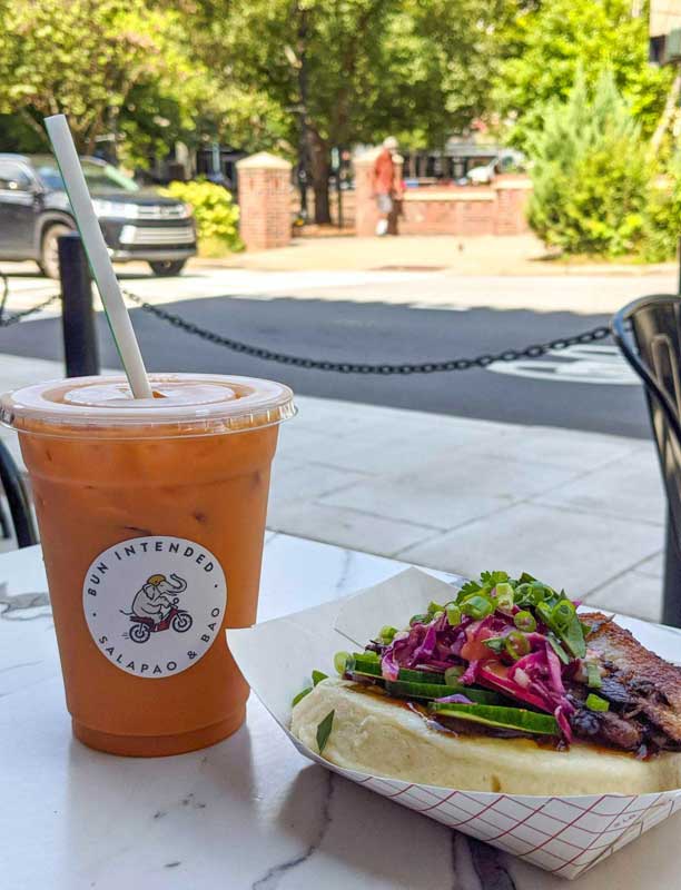 Thai iced tea and a Bao Bun from Bun Intended on an outdoor table