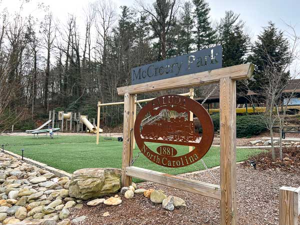 Sign for McCreery Park with a playground in the background in downtown Saluda, NC