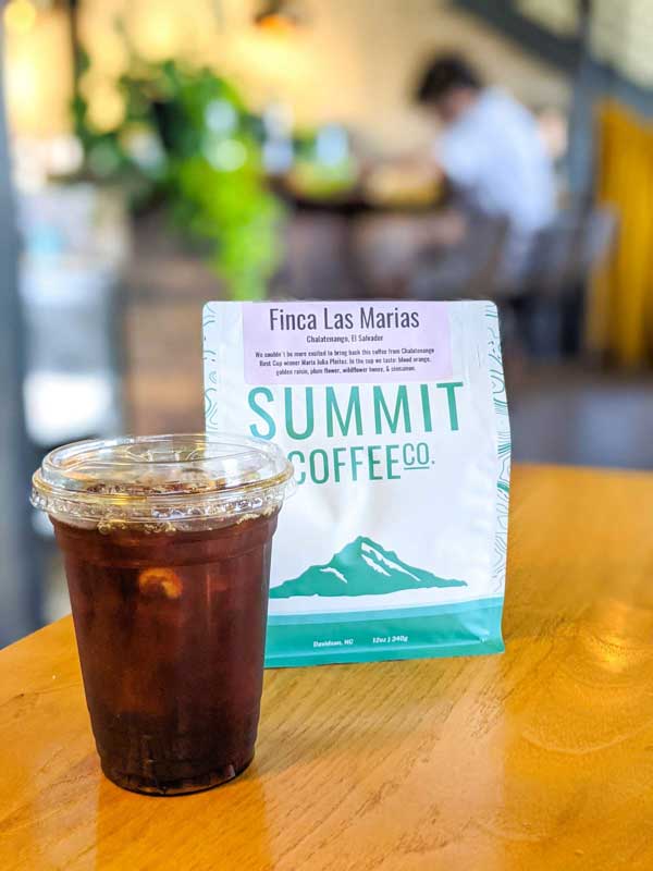 Iced coffee in front of a bag of Summit whole bean coffee