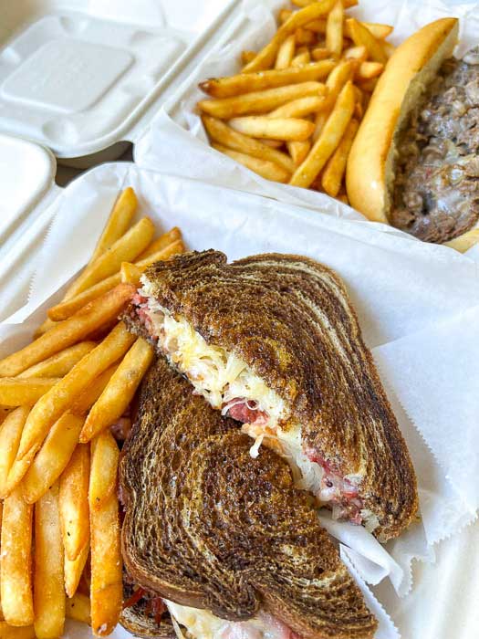 Reuben with french fries in a to go container from Asheville Sandwich Company