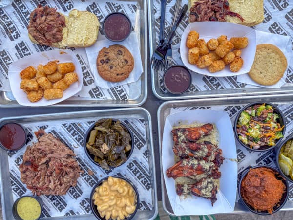 Trays of food at Bear's Smokehouse in Asheville, NC, showing wings, tator tots, pulled pork and Mac + cheese