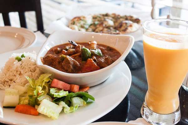 Plate with Indian food and a mango lassi next to it at Indian Garden in East Asheville