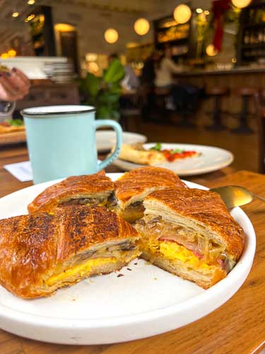 Croissant Bikini Sandwich from La Bodega by Curate with a cup of coffee in Asheville, NC