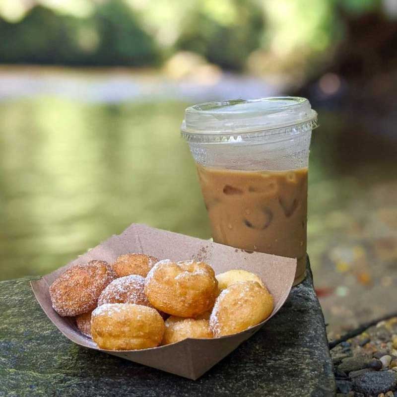 Donuts and a latte from The Velvet Cup perched on rocks with the Davidson River in the background