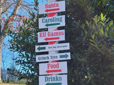 Sign at Tom Sawyer Christmas Tree Farm showing directions for trees, Santa, caroling, games and food